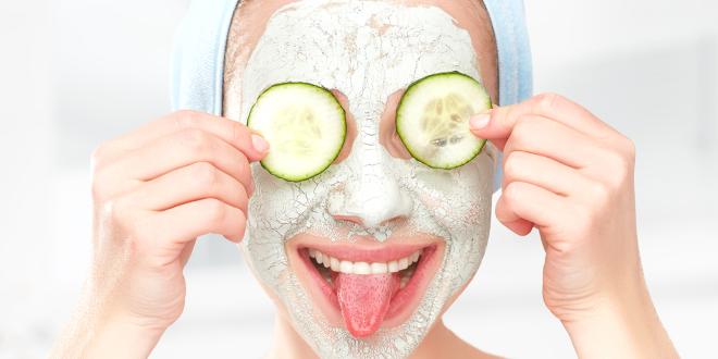 a woman with a facial mask and cucumbers over her eyes