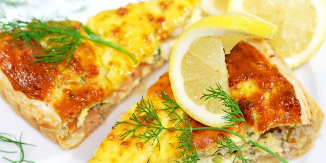 two slices of quiche, toped with sprigs of dill and a lemon wedge