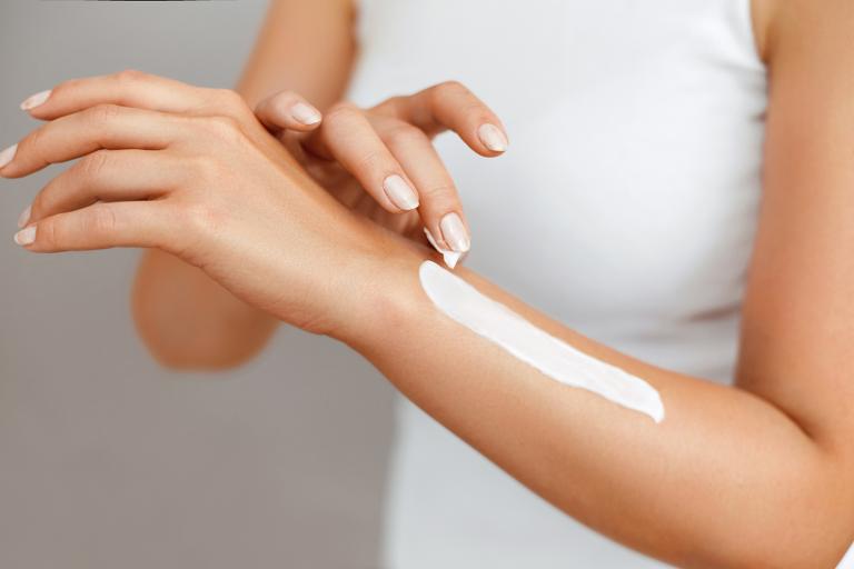 a woman applying skin lotion to her arm